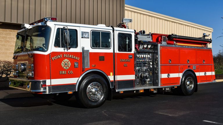 A red and white fire truck parked outside a building. The truck is labeled "Point Pleasant Fire Co." and "Engine 43" on the side. Various equipment and control panels are visible on the truck's side.